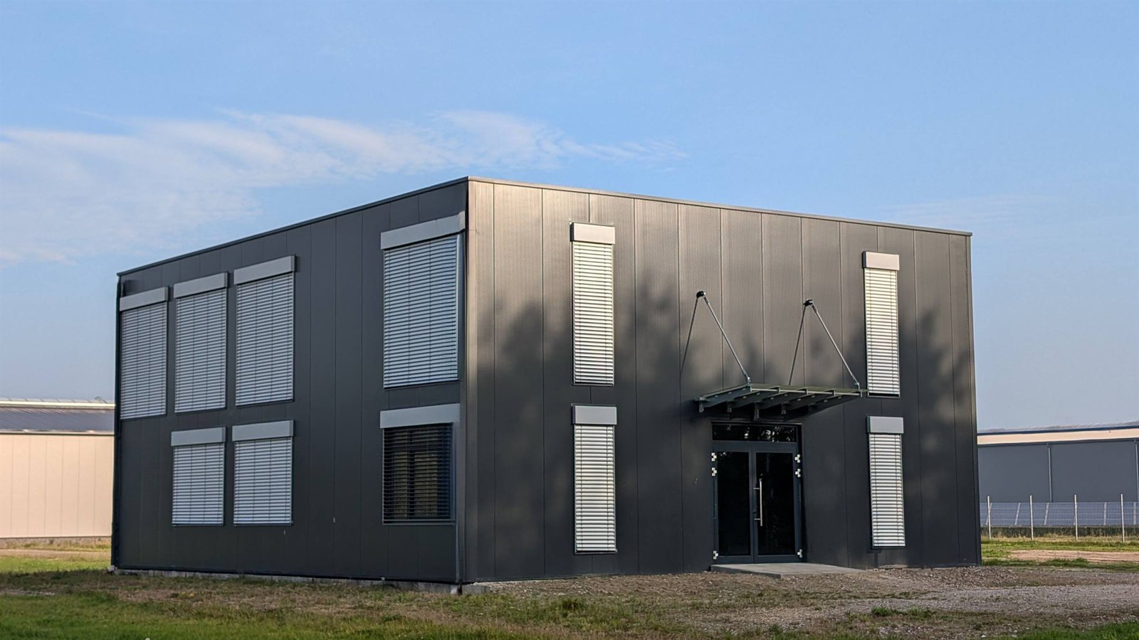 Anthrazitfarbener Bürocontainer auf einer Wiese