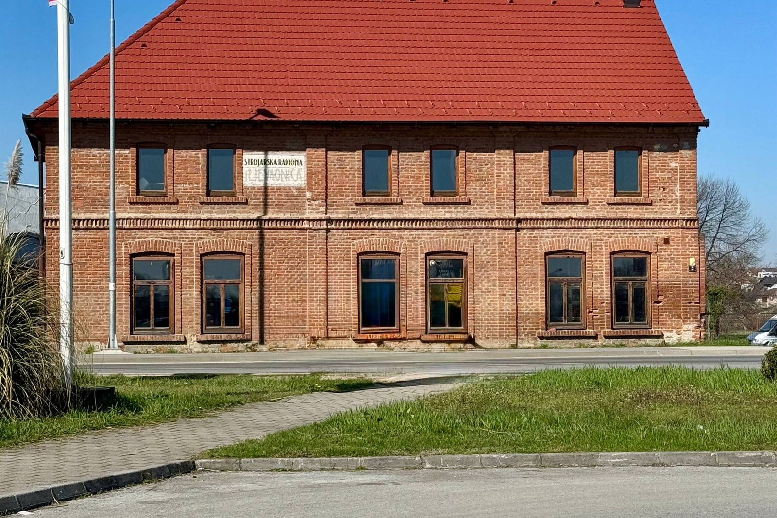 Backsteingebäude mit rotem Ziegeldach vor blauem Himmel